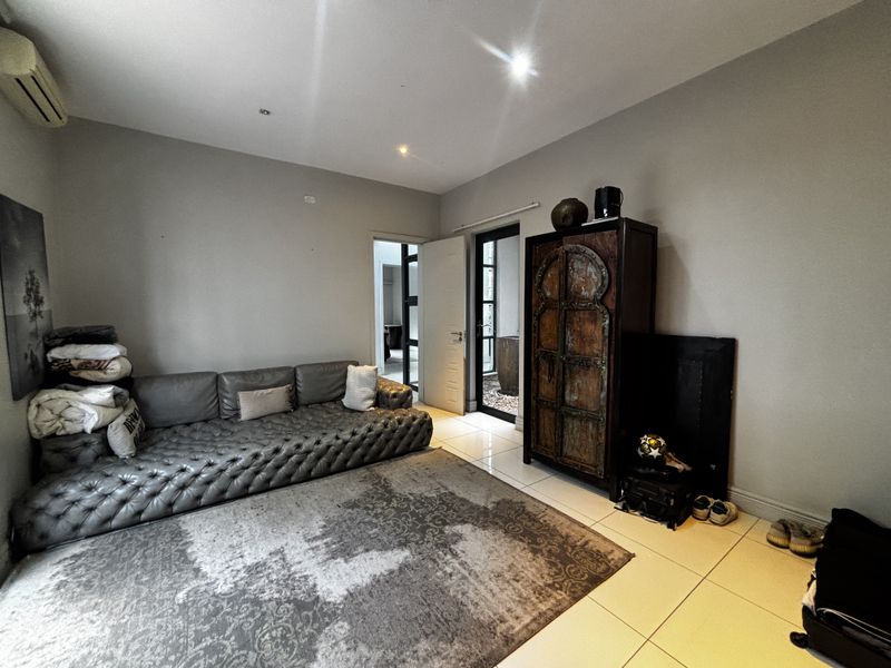 A living room featuring tiled flooring, recessed downlighting, and an air conditioning unit, with direct access to an outdoor area through a glass door.