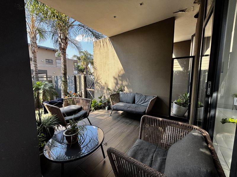 Covered patio area featuring tiled flooring and recessed lighting, providing a seamless transition to the outdoor garden space.