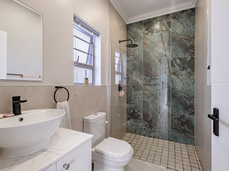Modern bathroom featuring a walk-in shower with striking feature tiling, a sleek vessel sink vanity, and contemporary black fixtures.