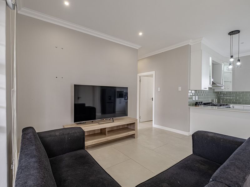 Open plan living area featuring tiled floors, recessed lighting, and a modern kitchen with stone countertops, subway tile backsplash, and integrated gas hob.
