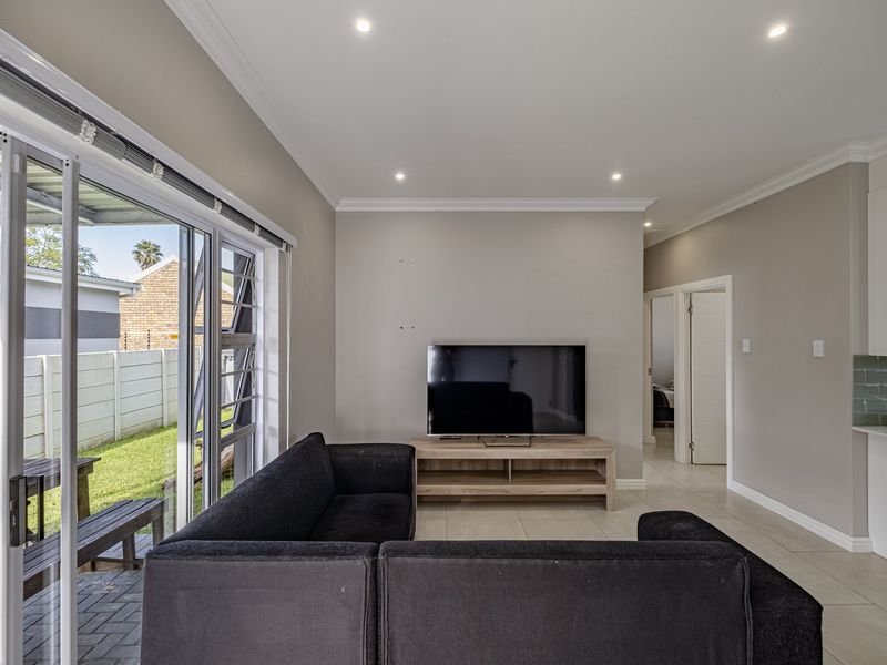 Open-plan living area featuring tiled floors, recessed lighting, and large sliding glass doors providing seamless access to the outdoor patio and garden.