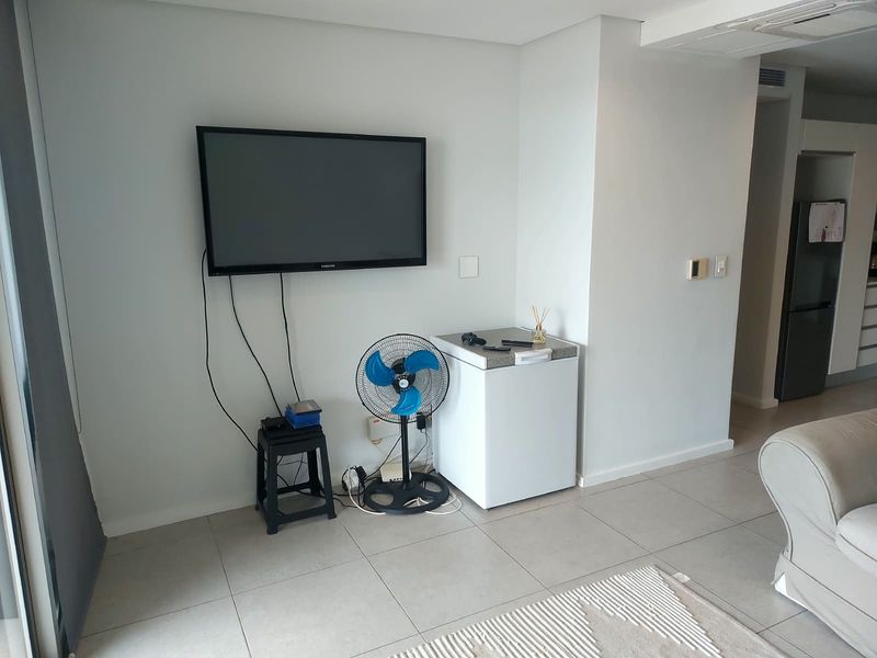 A bright living area featuring neutral tiled flooring and clean wall finishes, providing a versatile space for relaxation and entertainment.