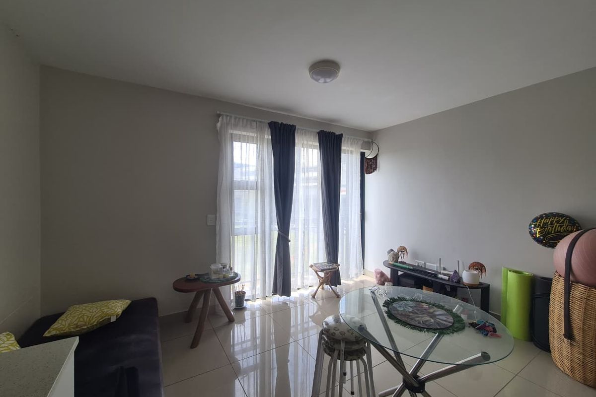 A bright living room featuring neutral tiled flooring and a large sliding glass door that provides natural light and access to the outdoors.