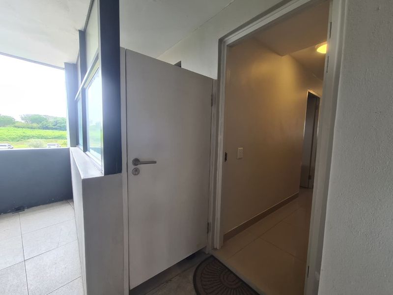 Entrance area featuring tiled flooring and a transition into the interior hallway, with access to an adjacent balcony space.