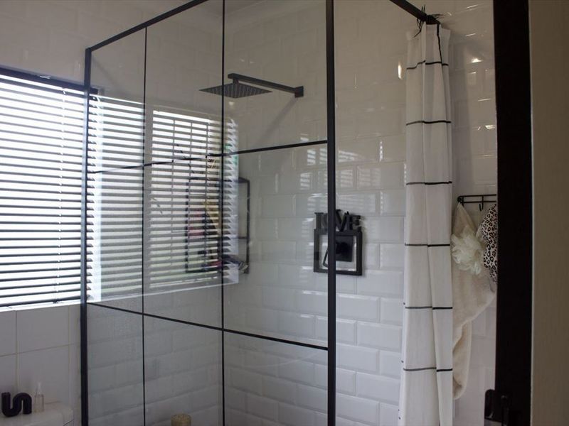 Modern bathroom featuring a walk-in shower with a black-framed glass screen, subway tile wall finishes, and a contemporary rain shower head.
