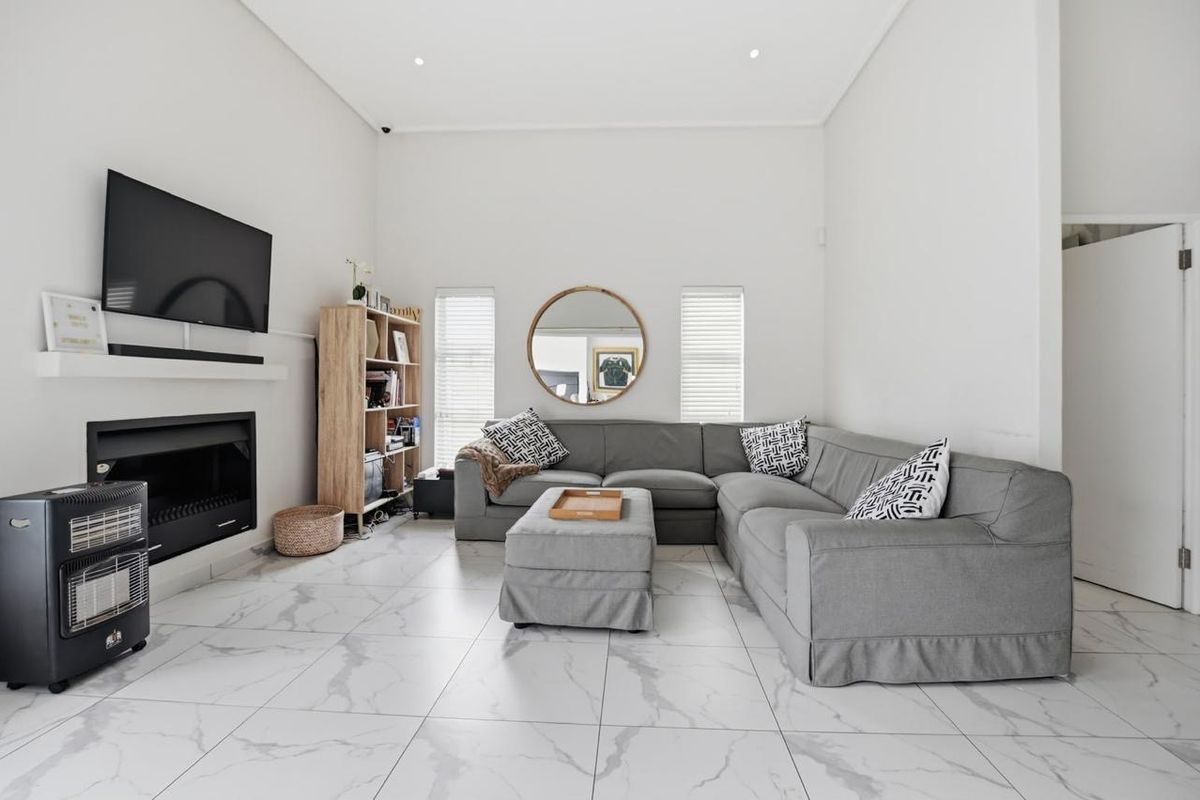 Spacious living room featuring high ceilings, modern marble-look floor tiles, and a built-in fireplace, creating a bright and contemporary atmosphere.