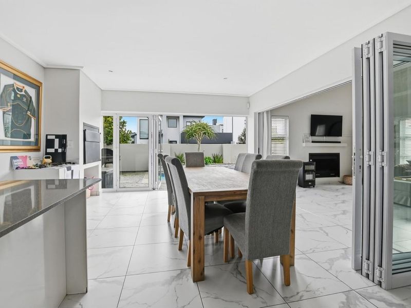Spacious open-plan dining area featuring large-format marble-look floor tiles, modern bi-fold doors leading to the patio, and a sleek built-in fireplace.