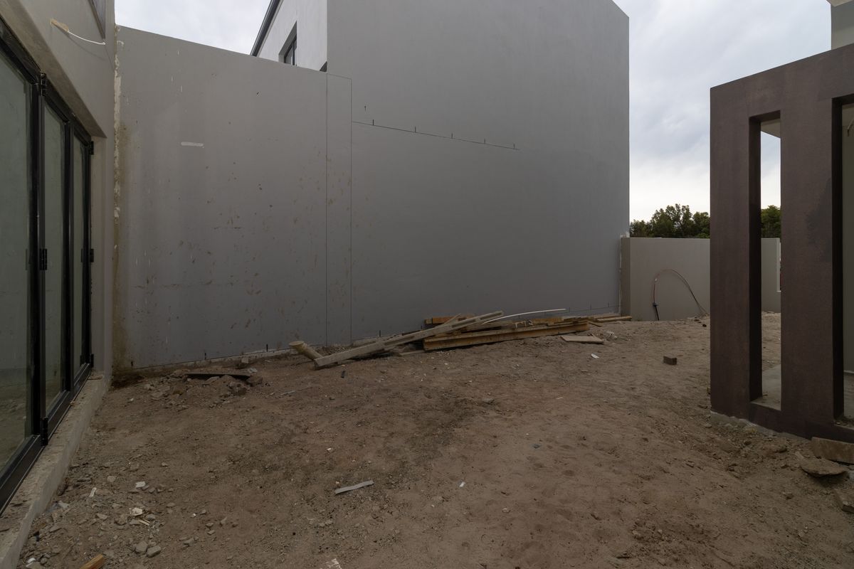 Rear exterior area of a modern property featuring bi-fold doors, currently in an unfinished construction state requiring landscaping and final surface finishes.