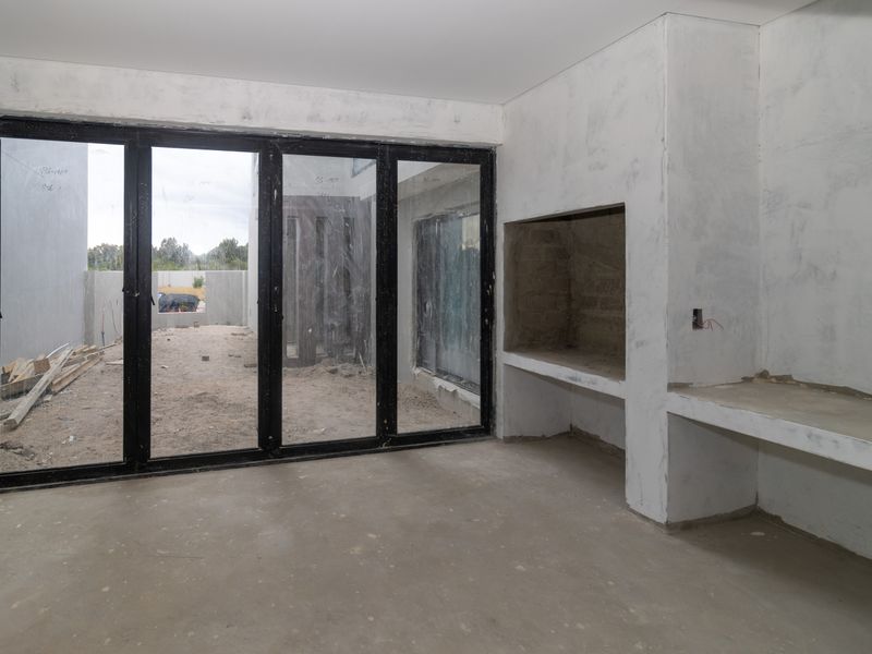 Unfinished living area featuring a built-in fireplace, concrete counter space, and large black aluminium folding doors leading to the exterior.
