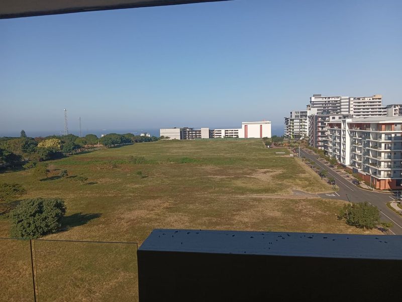 Elevated view overlooking a large open green space and surrounding residential apartment buildings.