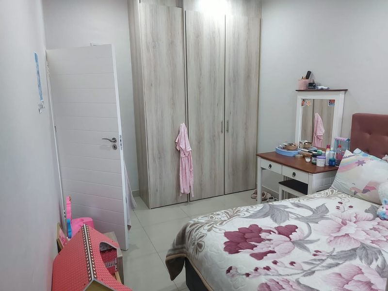 A well-maintained bedroom featuring light wood-grain built-in wardrobes and neutral tiled flooring, offering a clean and functional living space.
