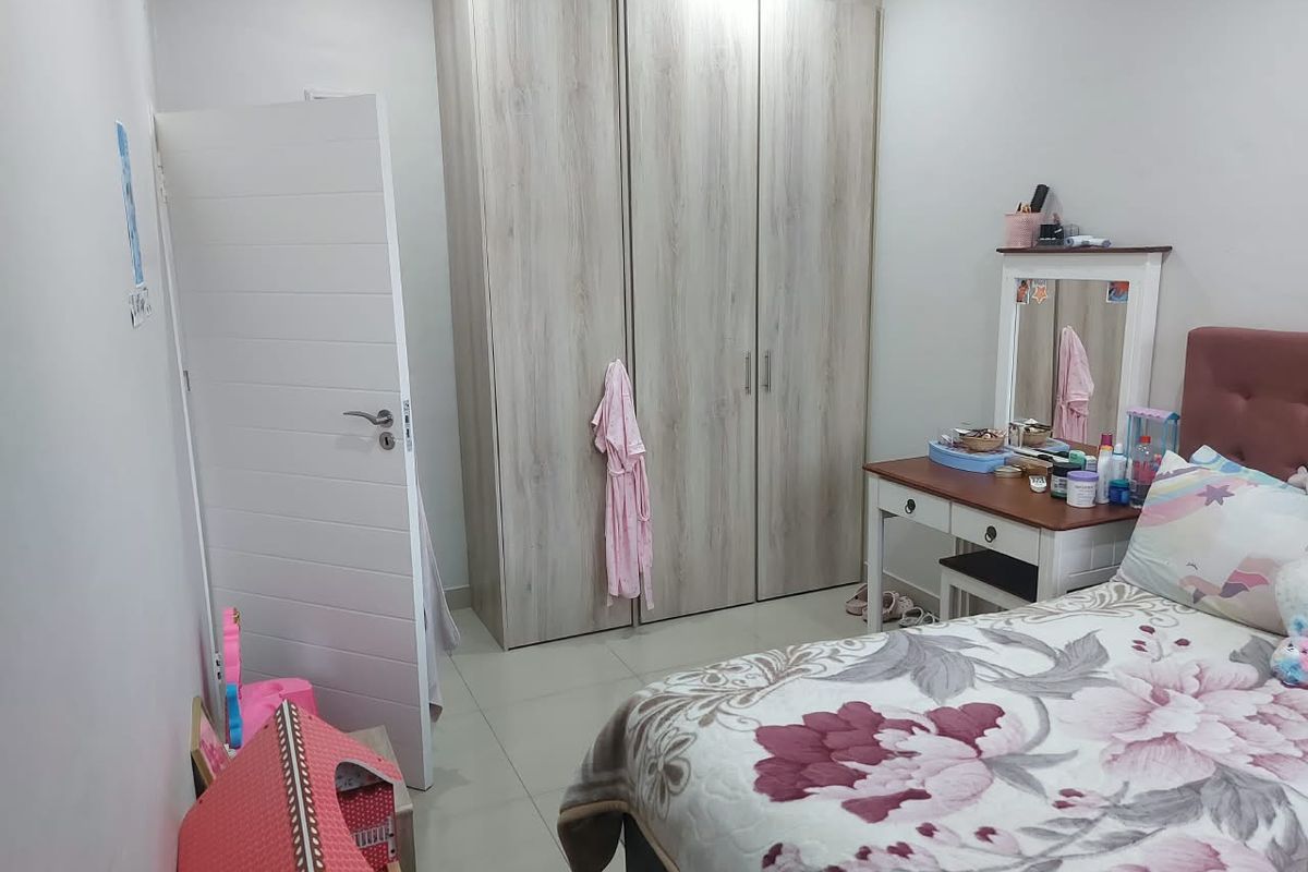 A well-maintained bedroom featuring light wood-grain built-in wardrobes and neutral tiled flooring, offering a clean and functional living space.