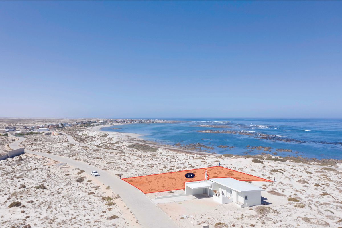 Aerial view of a coastal residential land plot marked with boundary lines, situated near the ocean with direct road access.