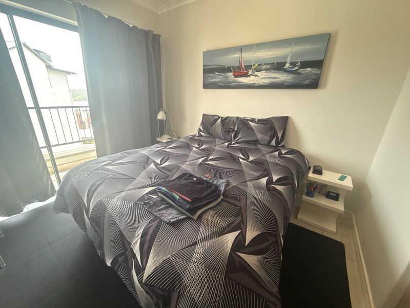 A bedroom featuring neutral walls, carpeted flooring, and a sliding glass door providing access to an attached balcony.
