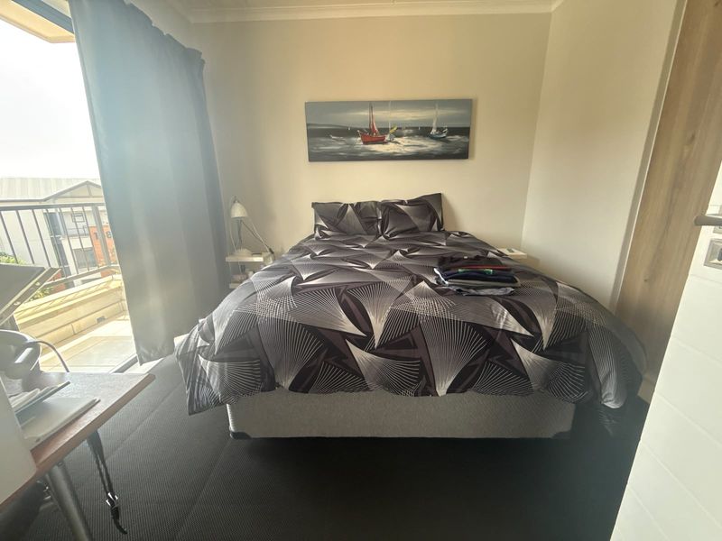 A bedroom featuring dark carpeting, a built-in wardrobe, and a sliding glass door providing direct access to an outdoor balcony.