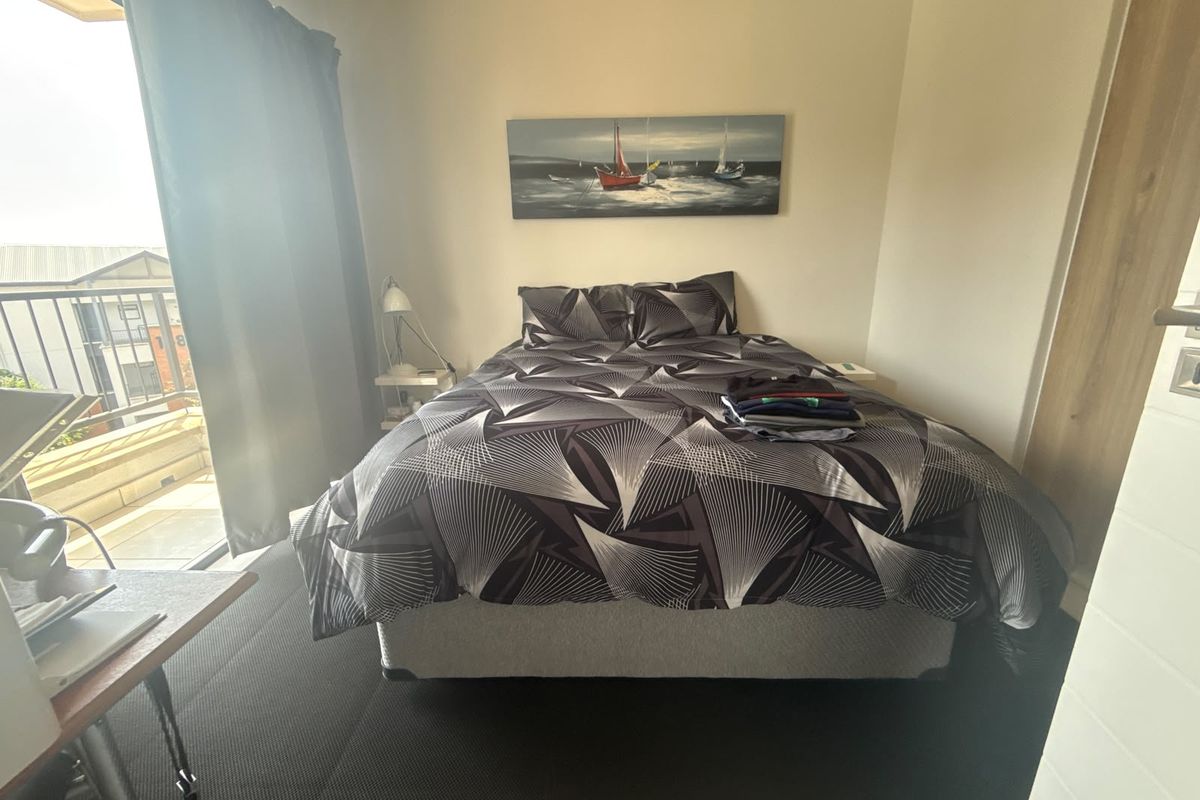 A bedroom featuring dark carpeting, a built-in wardrobe, and a sliding glass door providing direct access to an outdoor balcony.