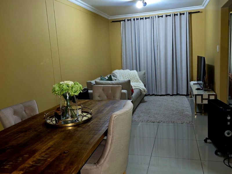 Open plan living and dining area featuring tiled flooring and ceiling cornicing, providing a functional space for relaxation and meals.