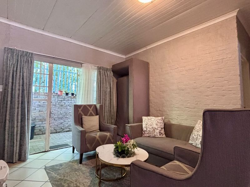 A cozy living room featuring a painted brick wall, tiled flooring, and a sliding glass door providing access to an outdoor patio area.
