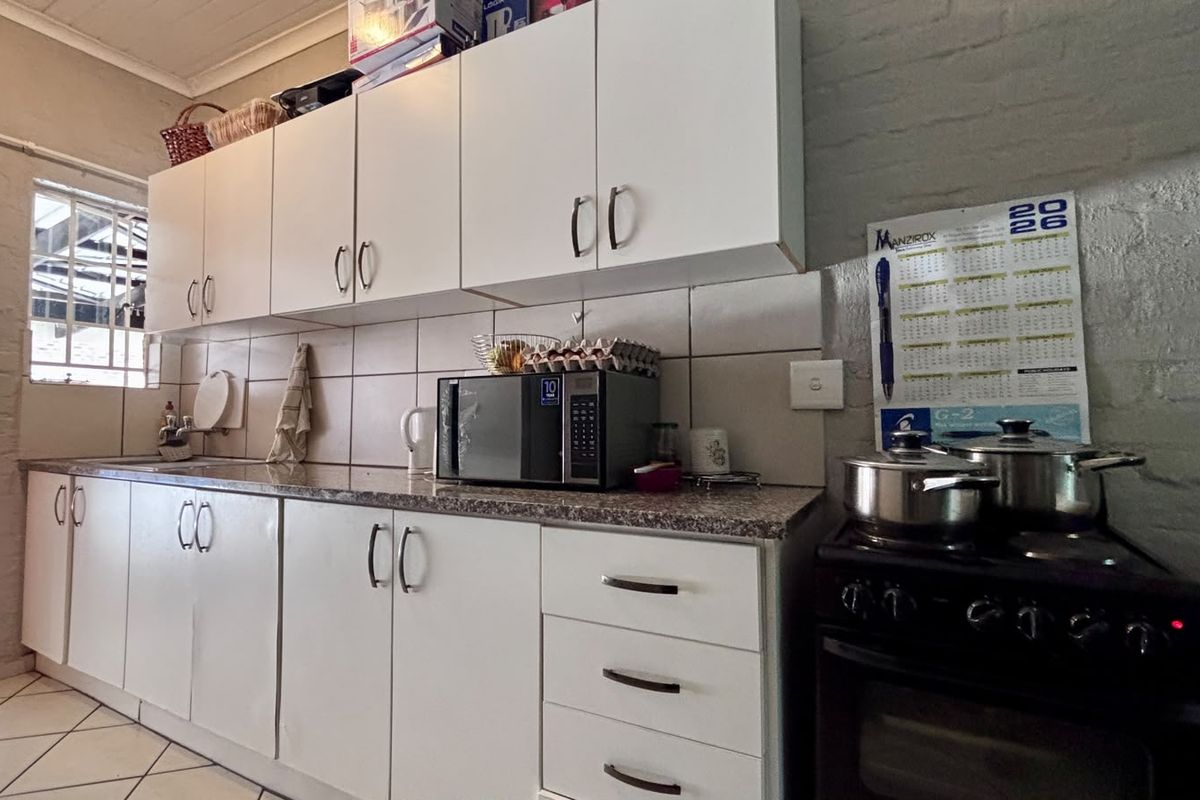 A functional kitchen featuring white cabinetry, granite countertops, tiled backsplash, and a freestanding stove, offering a practical layout for daily cooking.