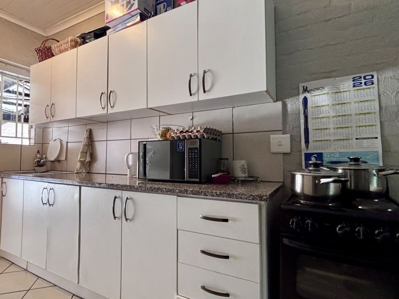 A functional kitchen featuring white cabinetry, granite countertops, tiled backsplash, and a freestanding stove, offering a practical layout for daily cooking.