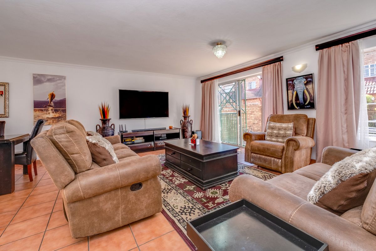 Spacious living room featuring tiled flooring, a central ceiling light, and sliding glass doors providing access to the outdoor area.