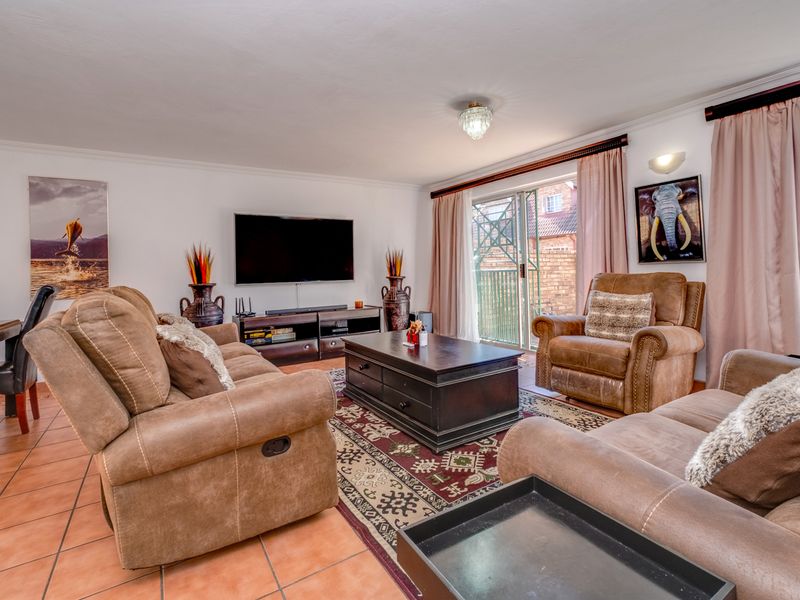 Spacious living room featuring tiled flooring, a central ceiling light, and sliding glass doors providing access to the outdoor area.