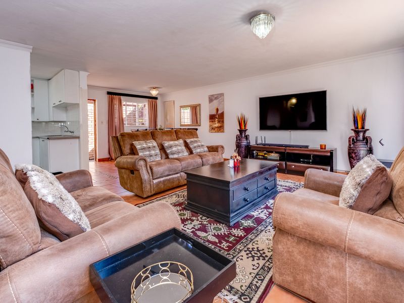Spacious open-plan living area featuring tiled floors, a connected kitchen space, and elegant lighting fixtures, creating a comfortable and functional home environment.