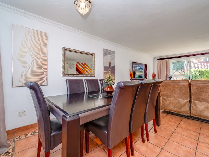 Open plan dining and living area featuring tiled flooring, coved ceilings, and a sliding glass door leading to the exterior.