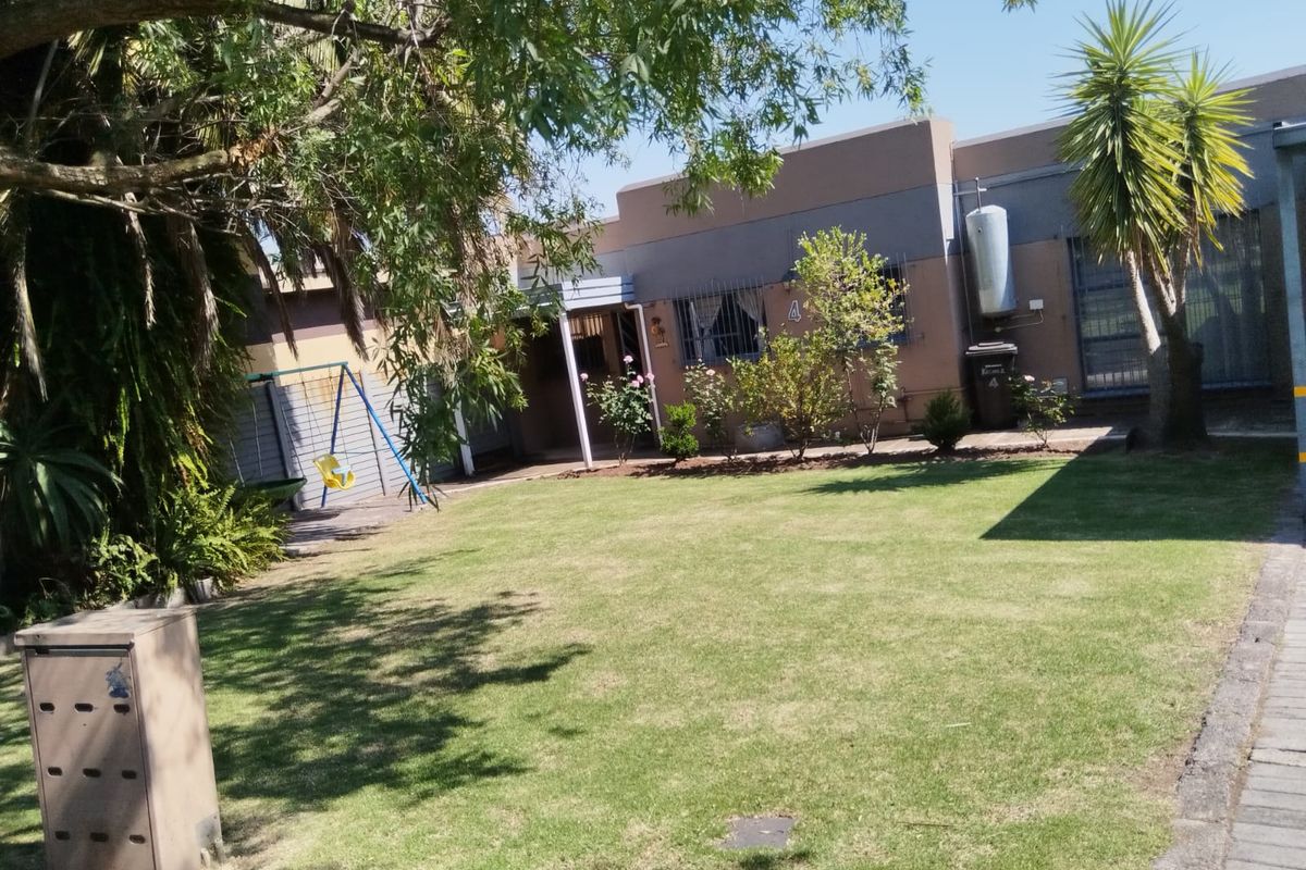 Rear view of the apartment featuring a private lawn, security bars on windows, and an external gas cylinder installation.
