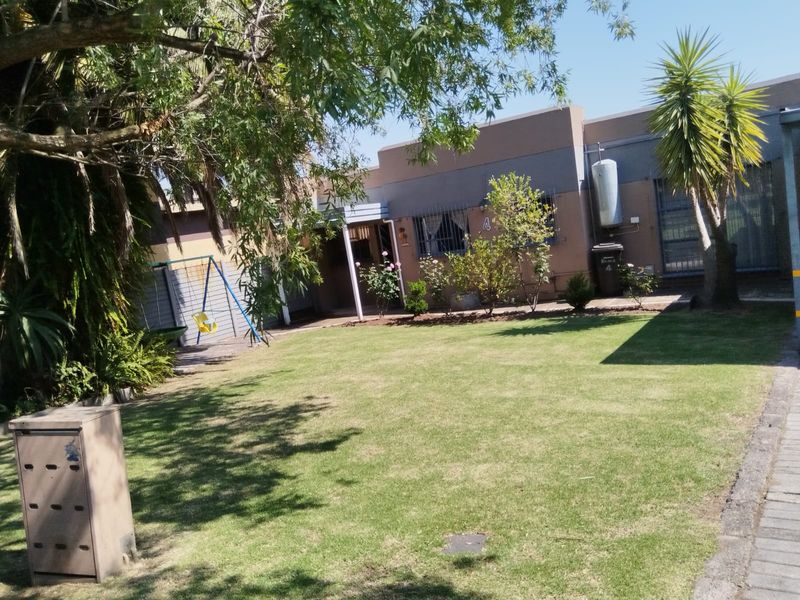 Rear view of the apartment featuring a private lawn, security bars on windows, and an external gas cylinder installation.