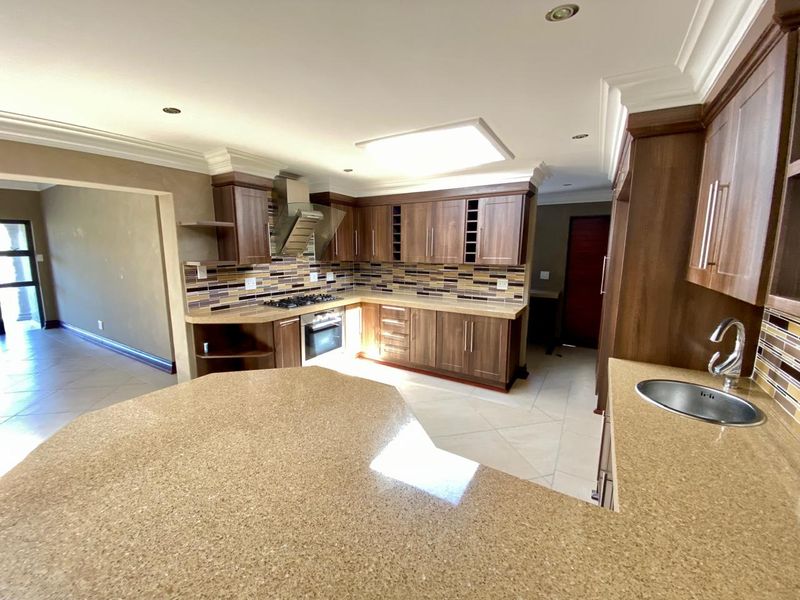 Spacious kitchen featuring dark wood cabinetry, granite countertops, mosaic tile backsplash, and integrated appliances, offering a functional layout with ample storage space.