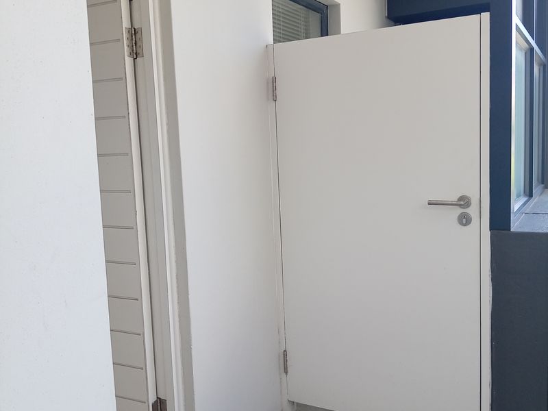 A clean, tiled balcony area featuring a white privacy screen and modern door access, providing a functional outdoor space.