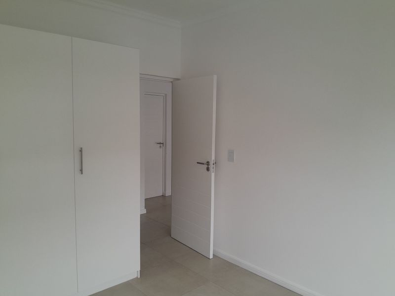 A clean, empty bedroom featuring neutral tiled flooring, built-in cupboards, and modern internal doors, offering a blank canvas for personalization.
