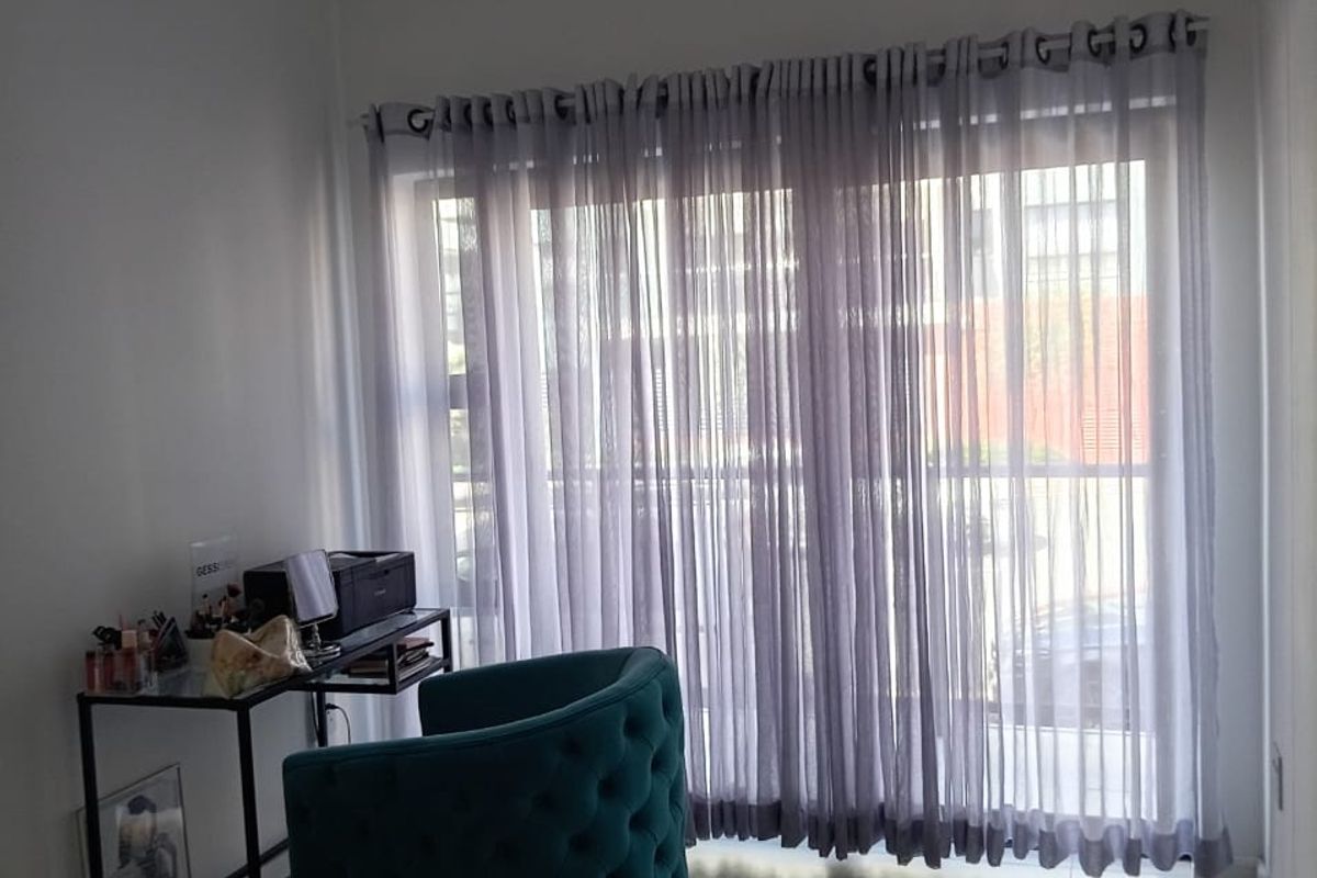 A bedroom featuring tiled flooring and a large sliding glass door with sheer curtains, providing natural light and access to an outdoor area.