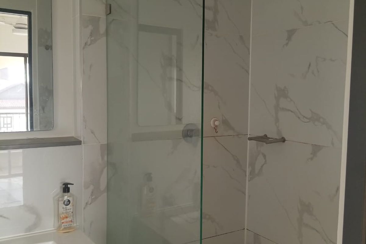 Modern bathroom featuring a walk-in shower with a rainfall shower head, marble-look wall tiles, and a sleek vanity unit with a basin.