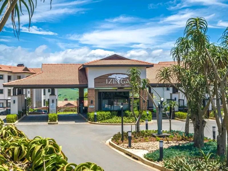 The main entrance and security gatehouse of the Izinga estate, featuring well-maintained landscaping, paved access roads, and a modern architectural design.