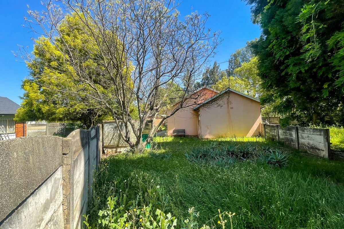Rear view of the property featuring a large garden area with mature trees and precast concrete boundary walls.