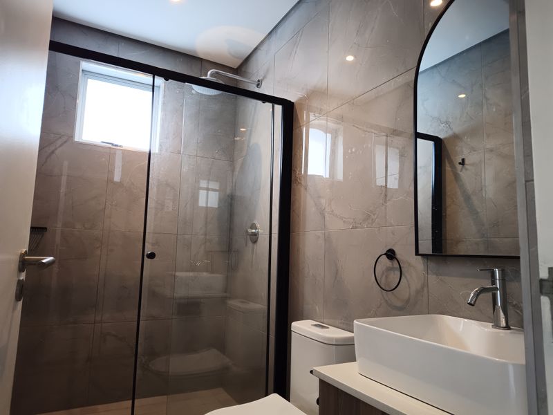 Modern bathroom featuring a glass-enclosed shower, contemporary vessel sink with vanity, and elegant grey porcelain wall tiles.
