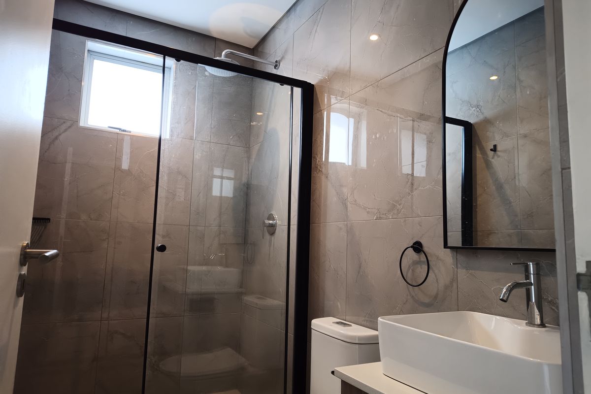 Modern bathroom featuring a glass-enclosed shower, contemporary vessel sink with vanity, and elegant grey porcelain wall tiles.