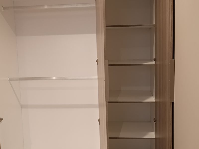 A modern built-in wardrobe featuring a combination of hanging space and shelving, finished in a clean wood-grain laminate.