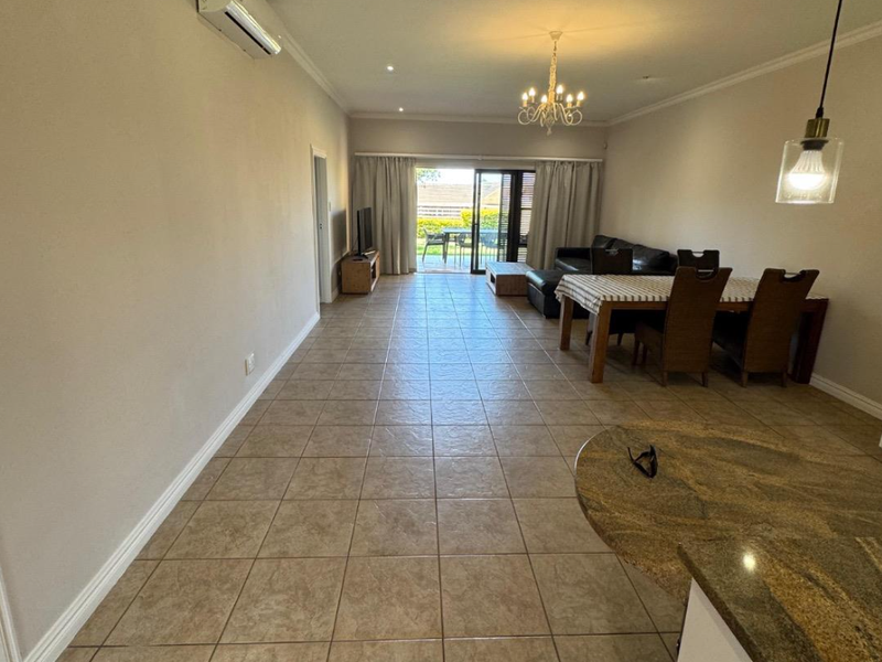 Spacious open-plan living and dining area featuring tiled floors, granite kitchen counter, and direct access to an outdoor patio through sliding glass doors.