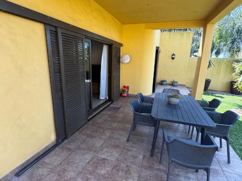 A covered patio area featuring tiled flooring, recessed lighting, and sliding glass doors providing access to the interior living space.