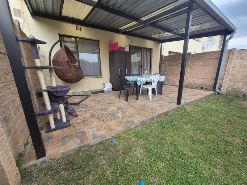 Covered patio area featuring tiled flooring and a metal roof structure, providing a functional outdoor space for relaxation and dining.