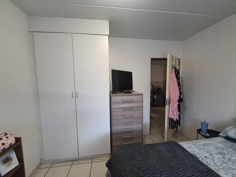 A functional bedroom featuring a built-in wardrobe and tiled flooring, providing a clean and practical living space.