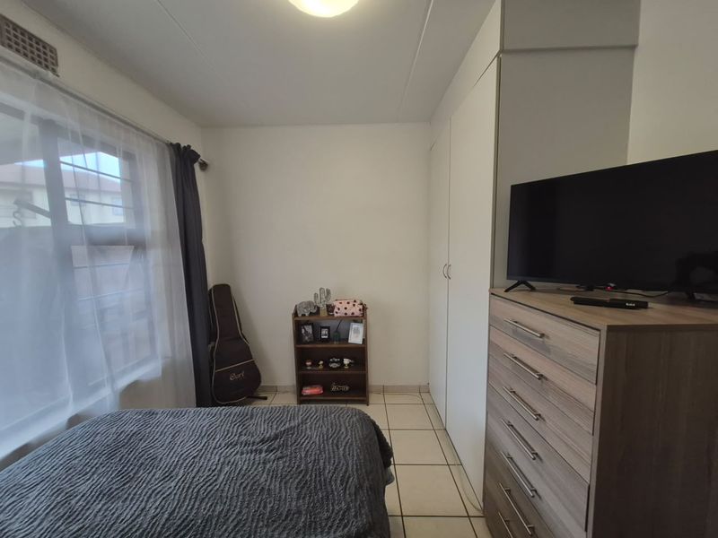 A functional bedroom featuring tiled flooring and built-in cupboards, providing essential storage space within the apartment.