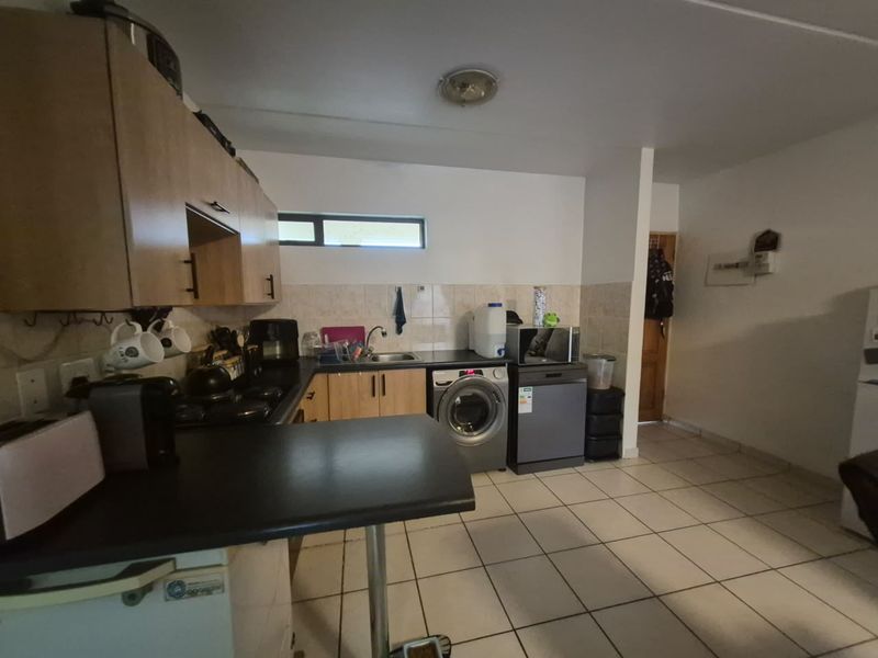 A functional kitchen featuring built-in cabinetry, tiled flooring, and integrated laundry and dishwasher appliances, offering a practical layout for daily use.