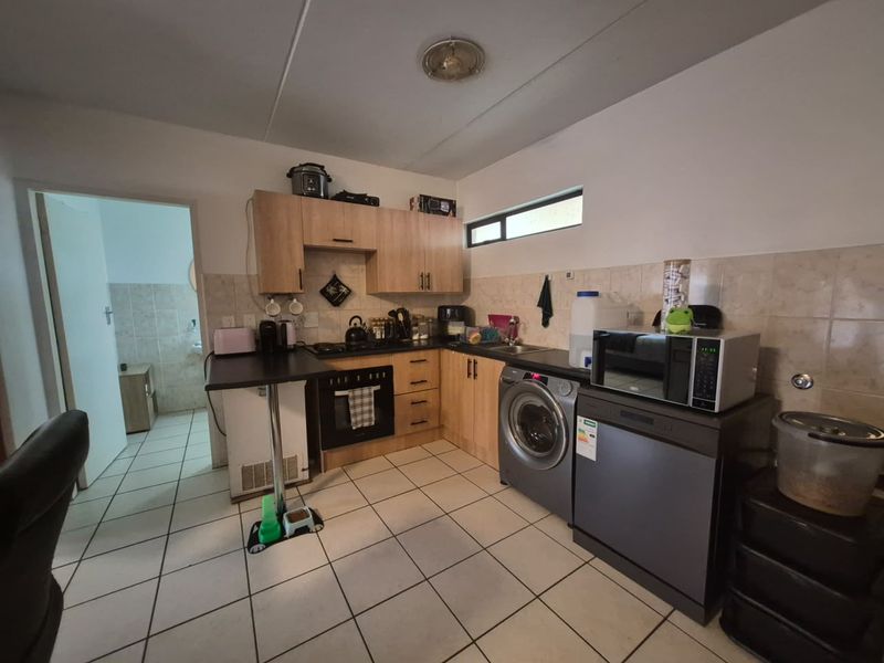 Functional kitchen featuring light wood cabinetry, tiled backsplash, integrated oven, and a breakfast bar, with direct access to an adjacent room.