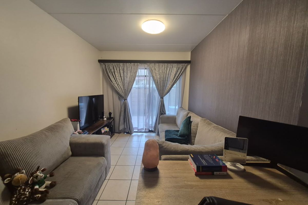 A comfortable living room featuring tiled flooring, a textured accent wall, and a sliding glass door that provides access to the outdoor area.