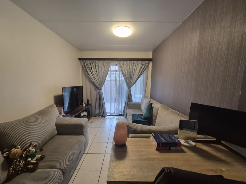 A comfortable living room featuring tiled flooring, a textured accent wall, and a sliding glass door that provides access to the outdoor area.