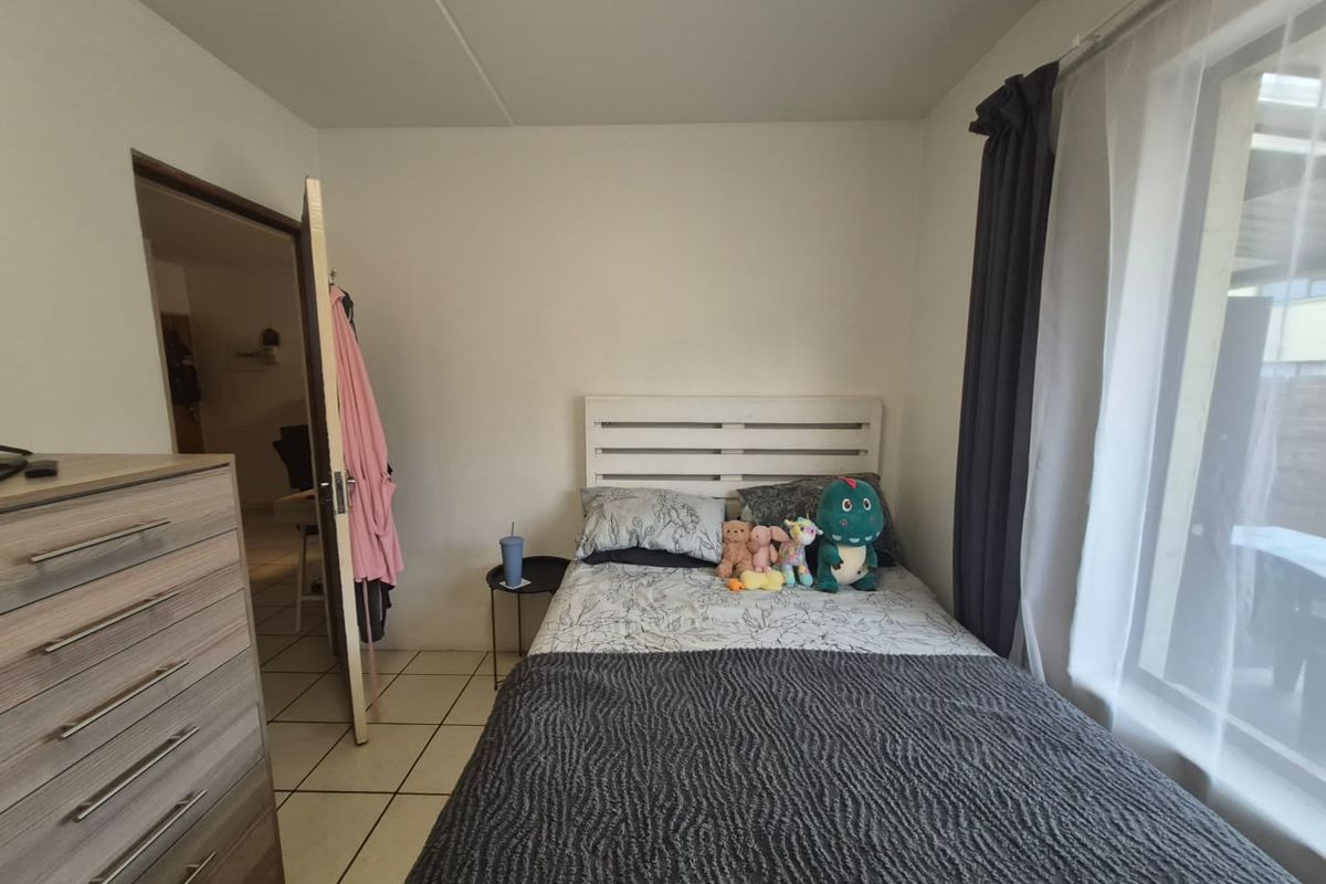 A functional bedroom featuring tiled flooring and large windows with curtain tracks, providing a neutral space ready for personalization.